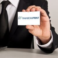 Eine Visitenkarte von Rainbowprint wird in die Kamera gehalten.