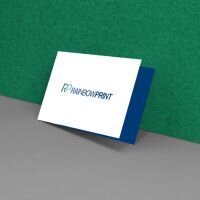 Eine Klapp-Visitenkarte von Rainbowprint, die an einer grünen Wand lehnt.