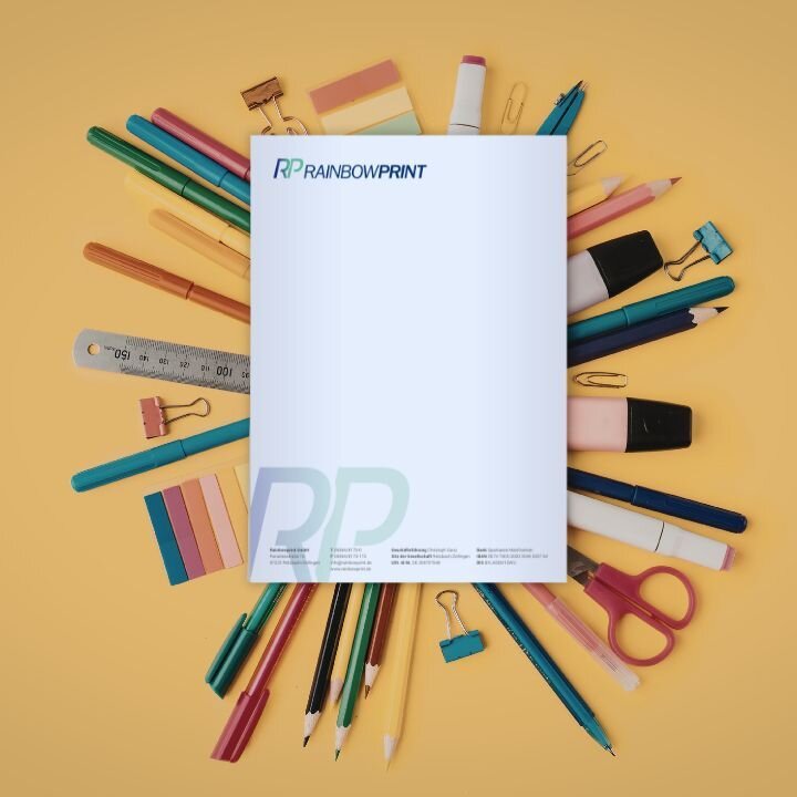 Briefpapier von Rainbowprint auf verschiedenen Buntstiften und Schreibmaterialien.
