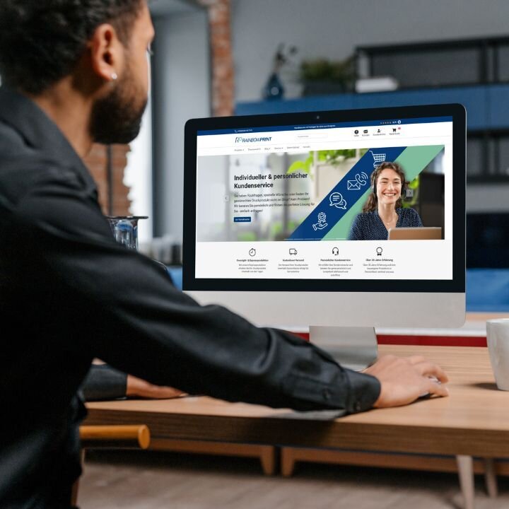 Eine Person, die an einem Computer sitzt und die Rainbowprint Website geöffnet hat.