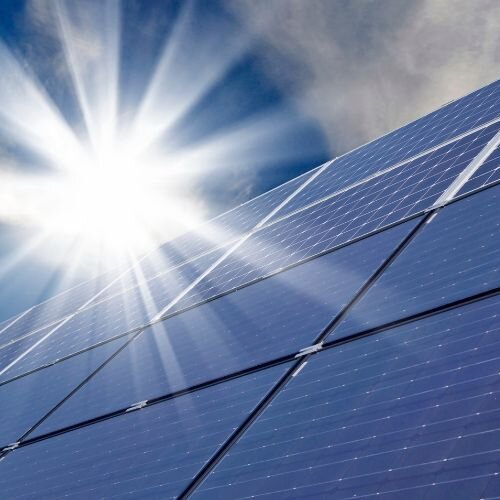 Eine Solaranlage, die Strom erzeugt. Im Hintergrund ist die Sonne zu erkennen.