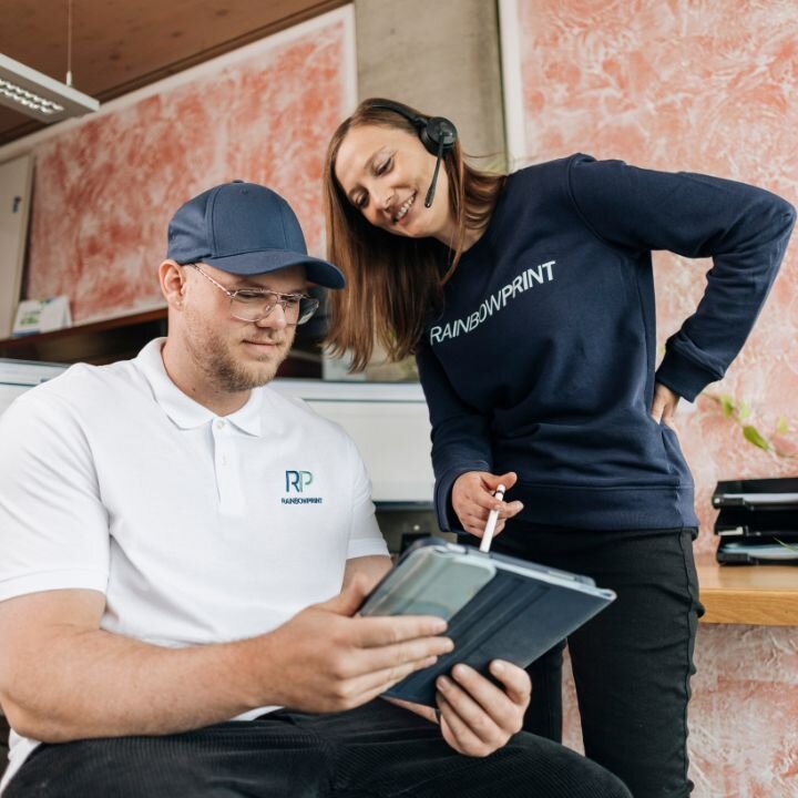 Im Kundenservice von Rainbowprint wird auf einem Tablet etwas erklrt.