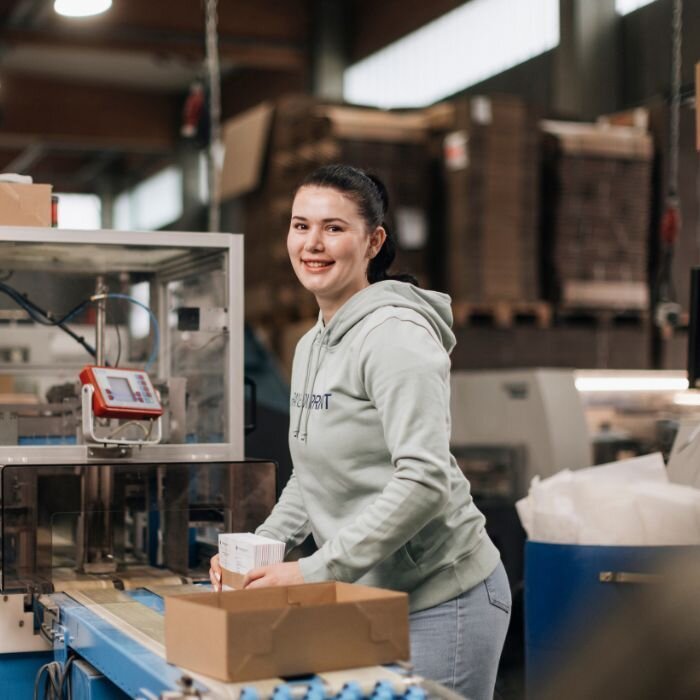 Eine Auszubildende von Rainbowprint bei der Weiterverarbeitung von Druckprodukten.