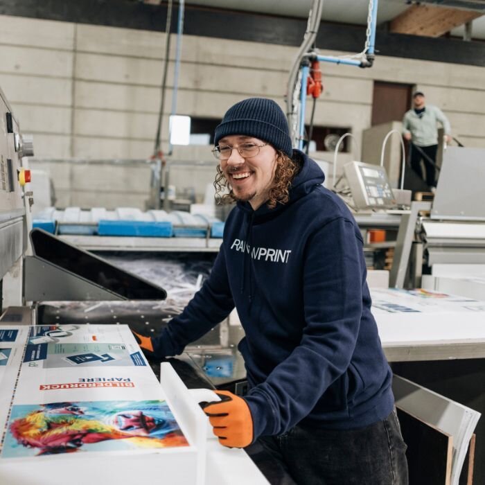 Ein Mitarbeiter von Rainbowprint in der Produktion an einer Maschine.