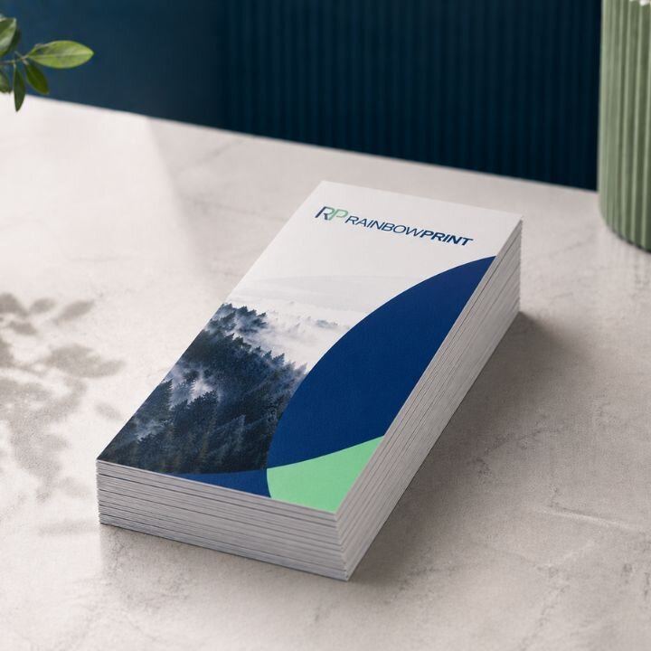 Ein Stapel Flyer DIN Lang von Rainbowprint GmbH auf einem hellen Untergrund.