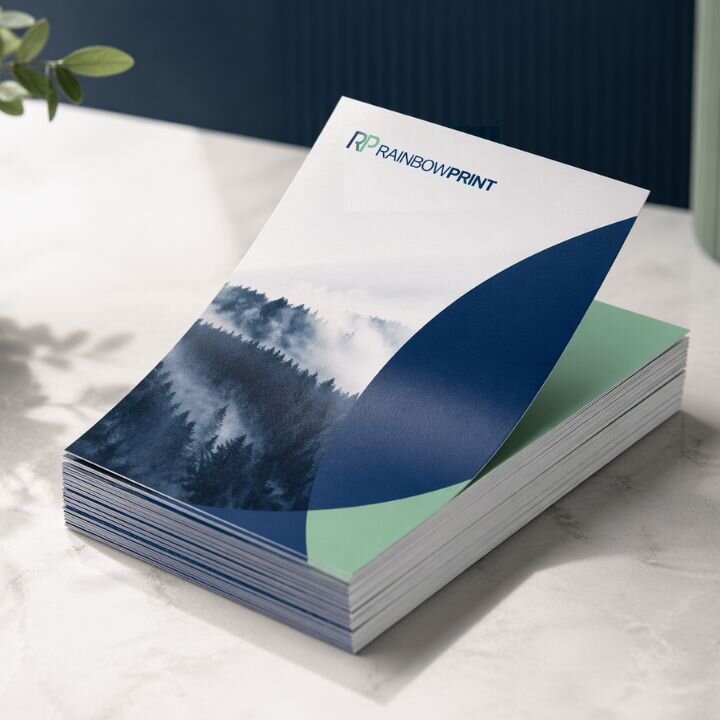 Ein Stapel Flyer von Rainbowprint GmbH auf einem hellen Untergrund.